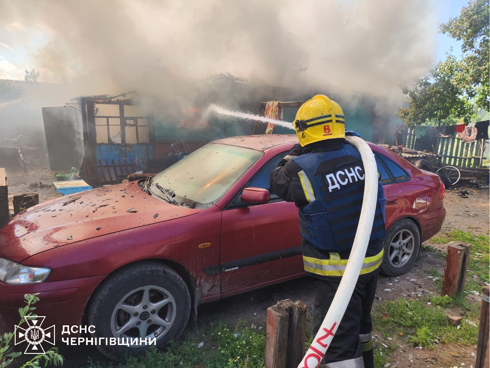 Фотографія рятувальник зі шланга поливає пожежу